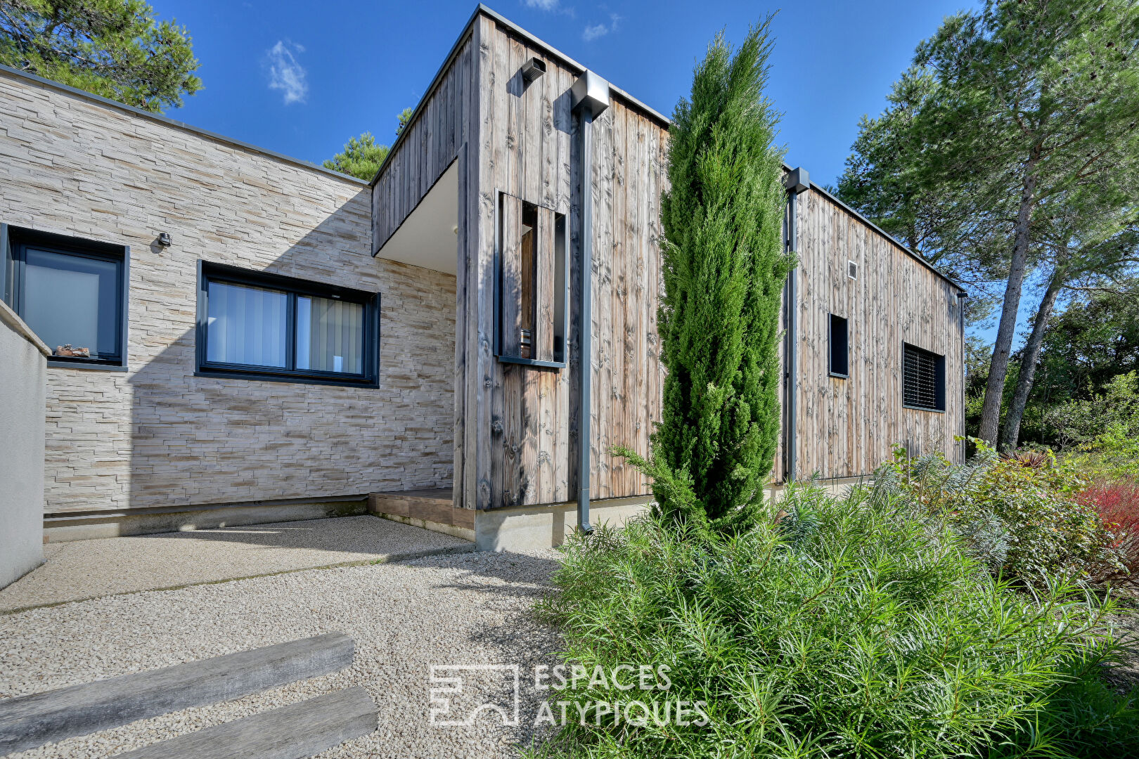 Single-storey wooden villa and its wooded garden