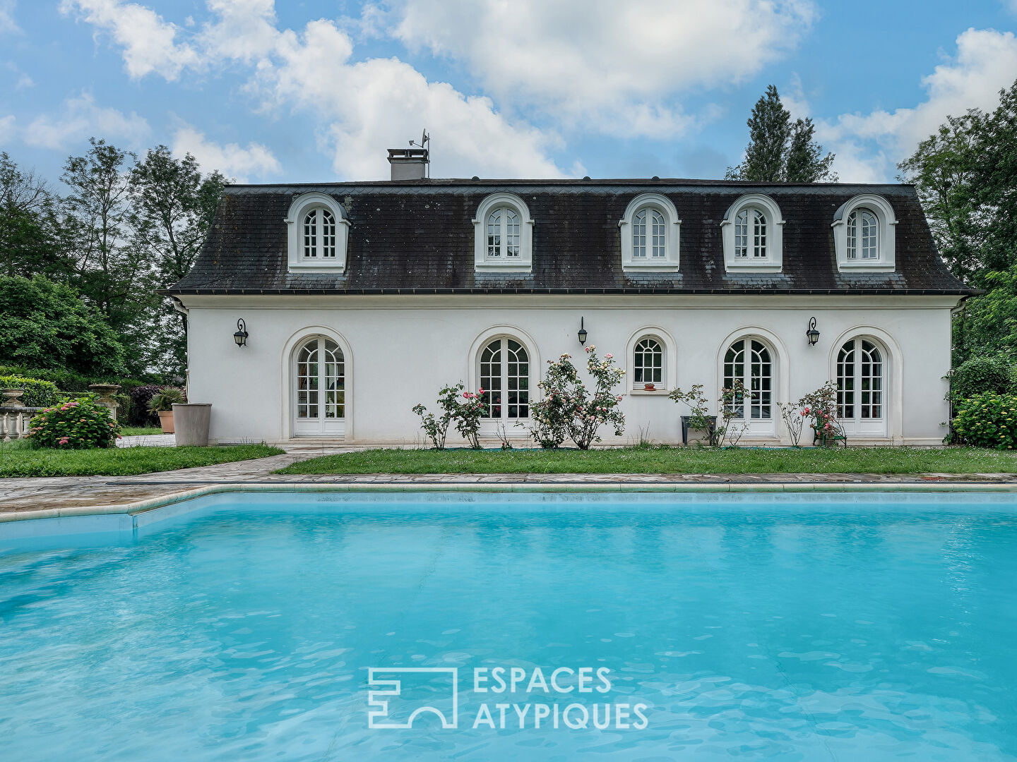 La maison spacieuse et son jardin avec piscine.