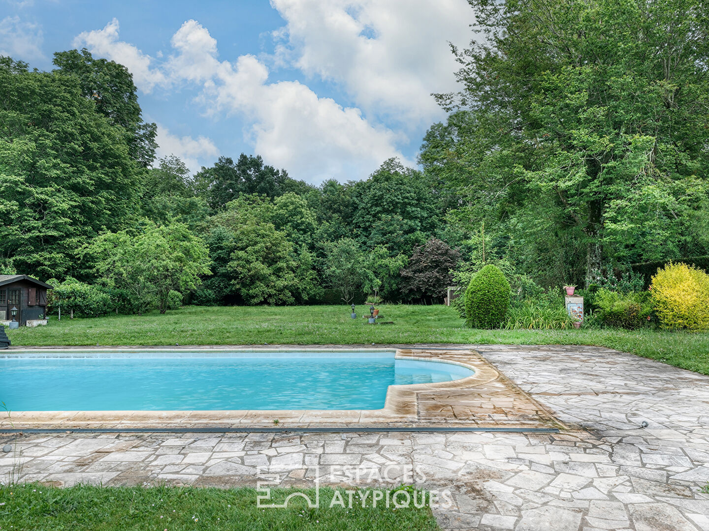 La maison spacieuse et son jardin avec piscine.